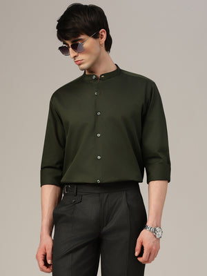 Man wearing a dark green shirt and black pants against a neutral background