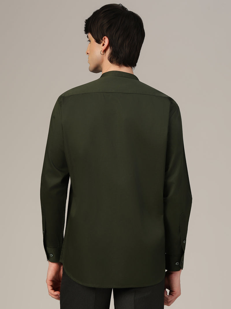 Person wearing a dark green shirt against a plain background