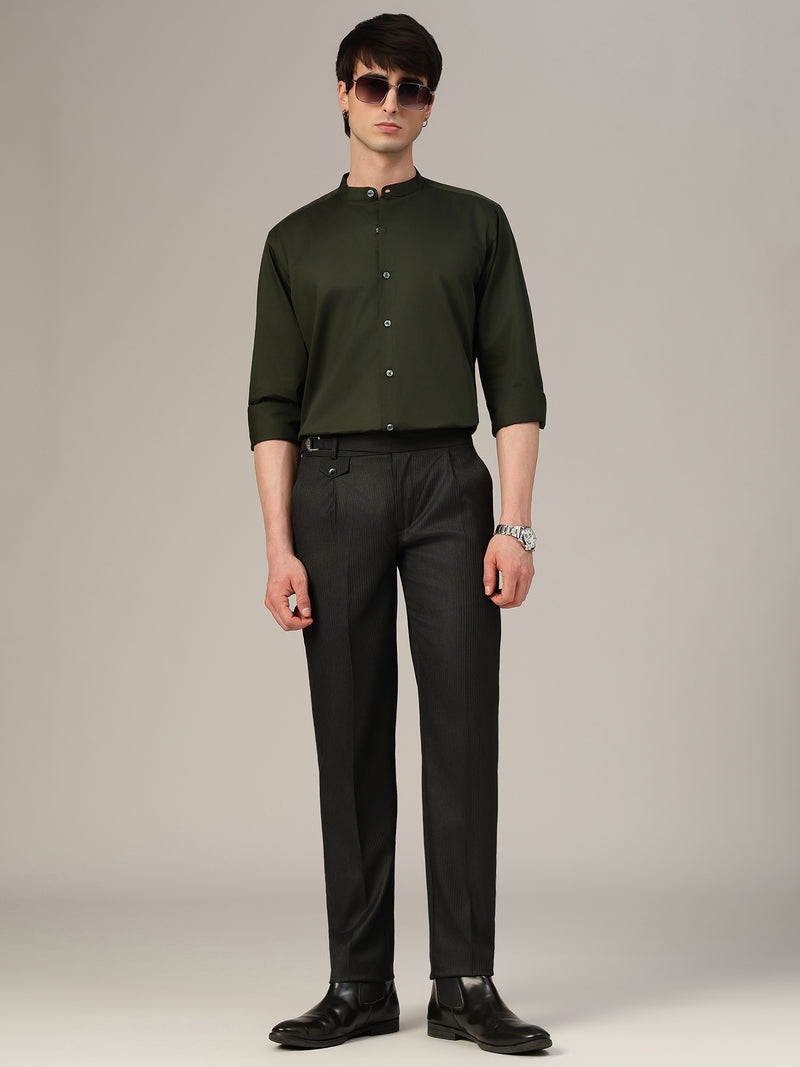 Man wearing a green shirt and black pants against a plain background