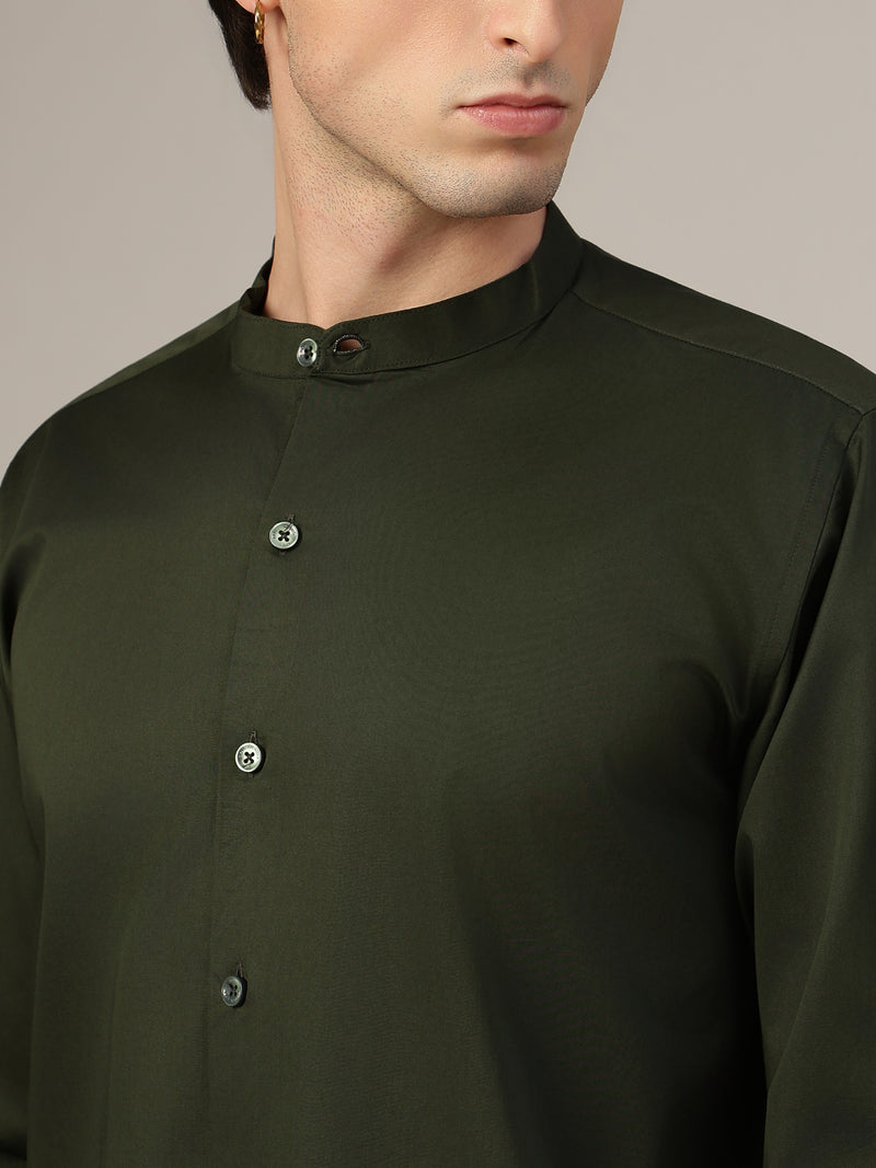 Close-up of a person wearing a dark green shirt with buttons on a neutral background