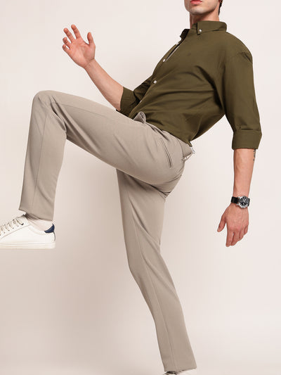 Person wearing a green shirt and beige pants on a plain background