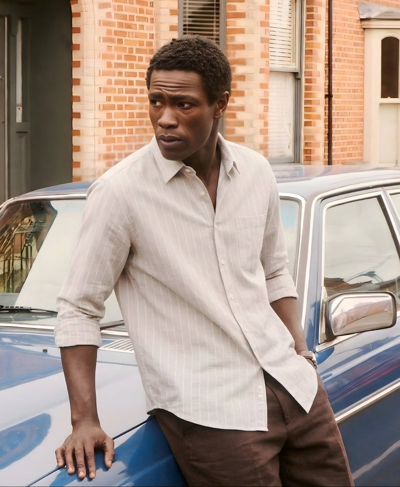 Man standing next to a vintage car in front of a brick building