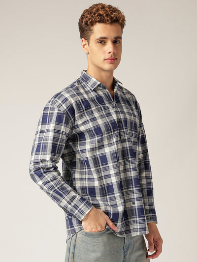 Man wearing a blue and white plaid shirt against a plain background