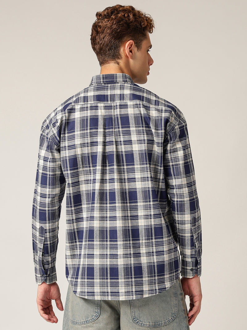 Person wearing a blue and white plaid shirt against a plain background
