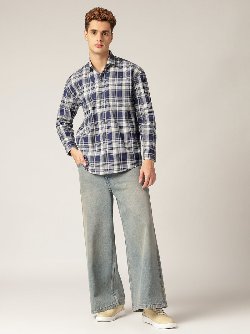 Man wearing a plaid shirt and jeans on a plain background
