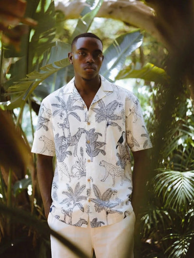 Man wearing a patterned shirt standing among tropical plants