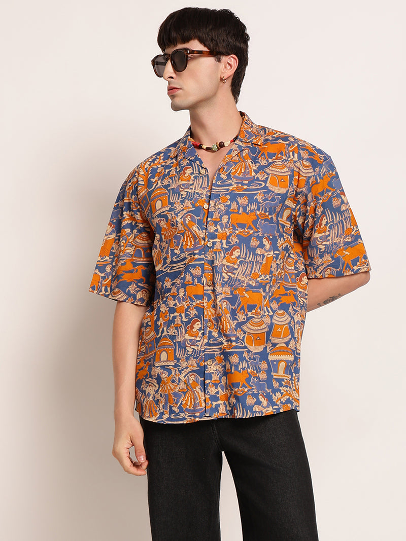 Person wearing a patterned shirt with orange and blue design on a plain background